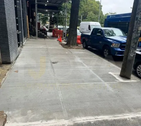 A long stretch of new sidewalk flags along a tree-lined street